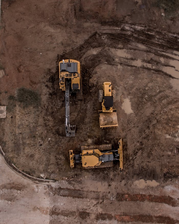 services-01 An aerial shot of heavy machinery at a construction site, including excavators and road rollers.