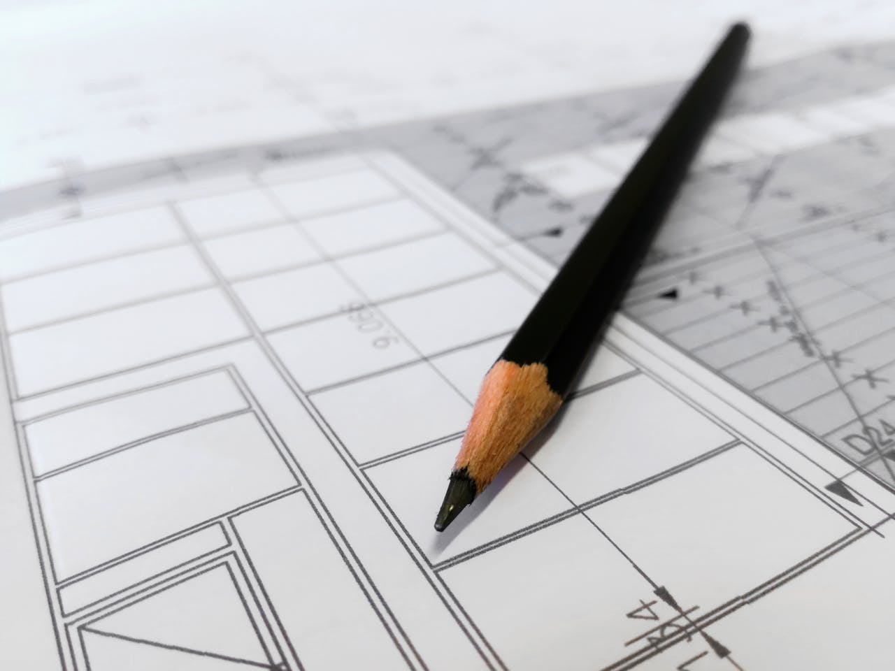 why-choose-us-03 Detailed image of a black pencil resting on architectural blueprints, ideal for design and planning themes.